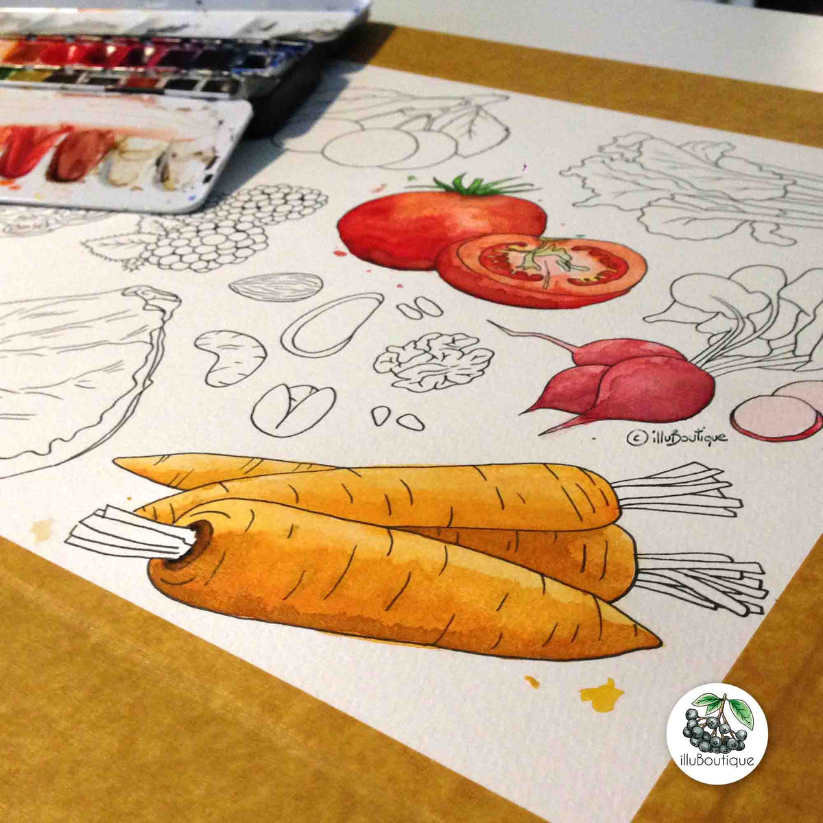 ein Foto als die Motive gemalt wurden. Das Aquarellpapier ist auf den Tisch geklebt, man sieht sie Illustrationen teilweise ausgemalt und im Hintergrund die Farbpalette